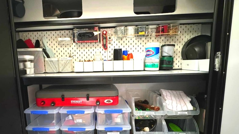 An IKEA pegboard on the back wall of a camper holds safety supplies and other items