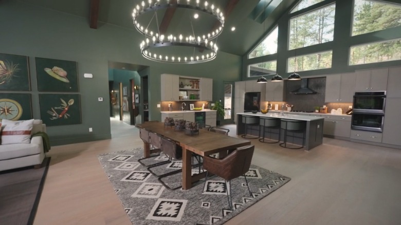 The open concept living area with green walls and a large light fixture